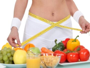 maigrir facilement Fruits et légumes disposés devant le corps d'une femme enlacé par un mètre ruban jaune