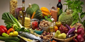 Table garnie de légumes, condiments, fruits, poissons, huile d'olive et graines