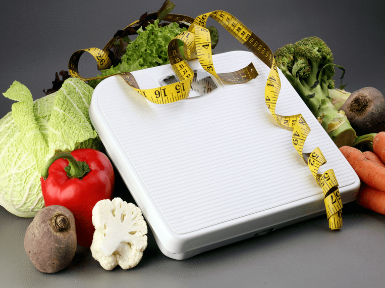  Pèse personne posé sur des fruits et légumes enlacés par un mètre ruban