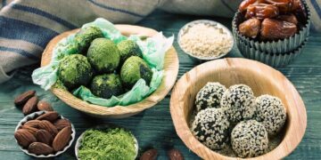 Energy balls au thé matcha et aux graines de sésame disposées au milieu de fruits secs et de graines