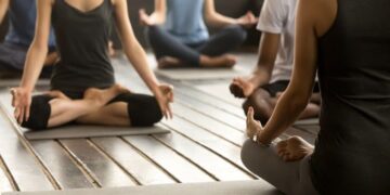 Yoga Groupe d'hommes et de femmes pratiquant une séance de yoga sur des tapis