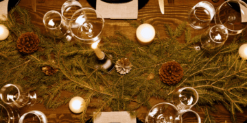 Table dressée pour les fêtes de fin d'année et décorée de pomme de pin, de gurilandes et de bougie
