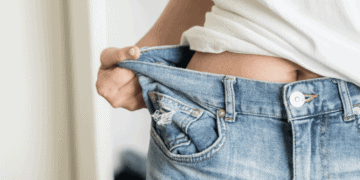 Perdre du poids plus rapidement Jeune femme tenant son jean étant trop grand pour elle